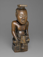 171. Ndop (portrait figure) of King Mishe miShyaang maMbul
Location: Democratic Republic of the Congo
Artist: ?
Date: c. 1760-1780 C.E.
Culture: Kuba peoples
Period/Style:
Medium/Material: Wood
Theme(s): authoritative position, spiritual presence 
Form: position shows a relaxed being in a higher position than others. Idealistic depiction of King's spiritual being. 
Function: took the place of the king in his absence
Content: male figure with a large head (represent knowledge), headwear, holding probably a cup, symbol marking on the base
Context: created after king's passing. earliest African wood sculpture and ndop in existence. Kept in king's shrine along with other 