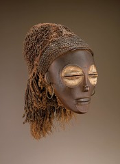 173. Female (Pwo) mask 
Location: Democratic Republic of the Congo
Artist: ?
Date: Late 19th-20th century C.E.
Culture: Chokwe peoples
Period/Style: ...
Medium/Material: thin wood, fiber, pigment, and metal
Theme(s): spirituality, fertility, birth
Form: mouth and eyes closed, deep red mask, kaolin (white powder connected to spiritual realm), circles
Function: danced/walked (gracefully); men honors founding female ancestors; often performed at the celebrations that mark the completion of initiation into adulthood
Content: eyes are abstractly large, symmetrical face, narrow chin, broad face and forehead
Context: men that honored women in Chokwe society that were young and gave birth
Cross Cultural Connection(s): ...