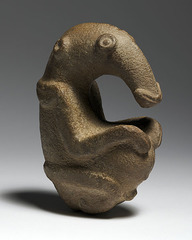 9. Ambum Stone
Location: Ambum Valley, Enga Provine, Papua New Guinea
Artist: N/A
Date: c. 1,500 B.C.E
Culture: (probably) ancient Oceania
Period/Style: Prehistoric, Neolithic
Medium/Material: Greywacke
Theme(s): Birds, pestle
Form: Made out of greywacke, probably to get a rich, brown color to represent the importance of animals. 
Function: Considered sacred and credited with supernatural powers by present day people of the region.
Content: A bird-like figure that sits like a human calmly.
Context: It has a higher level of figurative qualities than other pestles and may be in a unique class of its own.